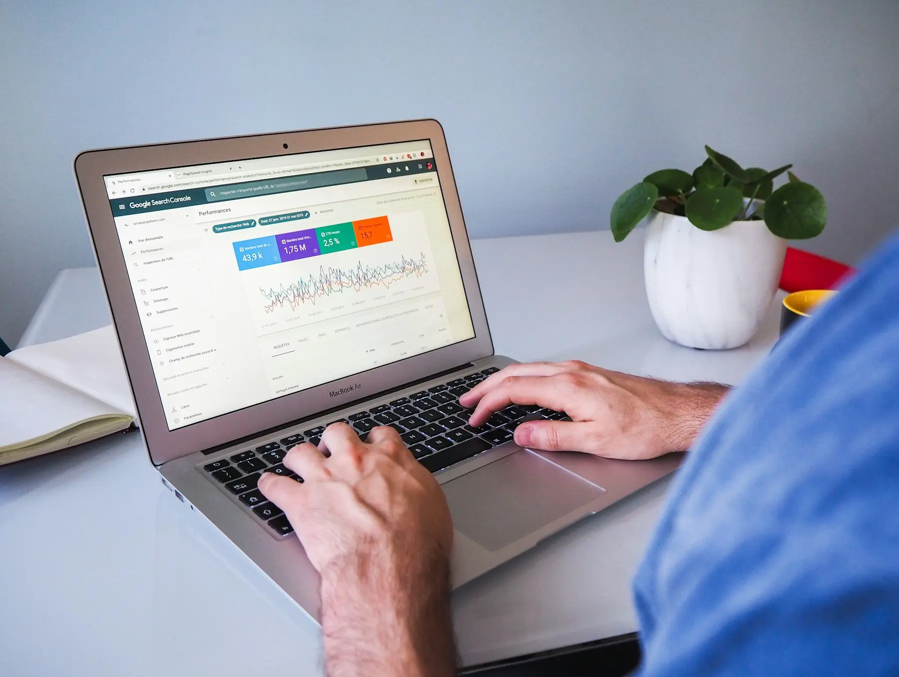 Hands typing on a laptop showing a search performance dashboard